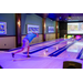 A man throwing a bowling ball down a lane towards pink bowling pins.