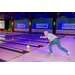 A man standing at the front of a bowling lane still in his throwing stance.