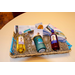 A wooden gift basket with two types of wine, two wine glasses, candy, gift cards, and a shirt.