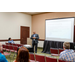 Individuals in a room watching a man give a presentation.