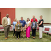 A group photo of individuals standing in the middle of a circle of chairs.