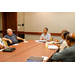 A woman sitting at the head of a table speaking to five other individuals.