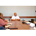 Anthony Goodson, Jr. sitting and the head of a table listening to others speaking.