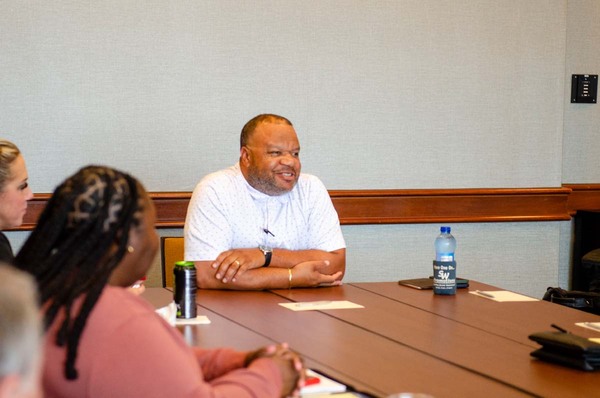 President Anthony Goodson, Jr. smiling while listening to others speak.