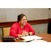 A woman in a pink cardigan smiling big.