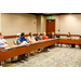 Several individuals sitting around a long u-shaped table.