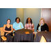 Four women sitting behind small round tables.