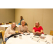 Four individuals sitting and standing around big round tables.