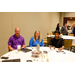 Three individuals with coffees sitting around a table.