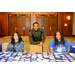 Three individuals sitting and standing around a table full of name badges.