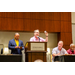 A man in a pink shirt at the podium and holding up a fidget spinner.