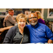 A man and a woman sitting next to each other. The man has his arm around her.