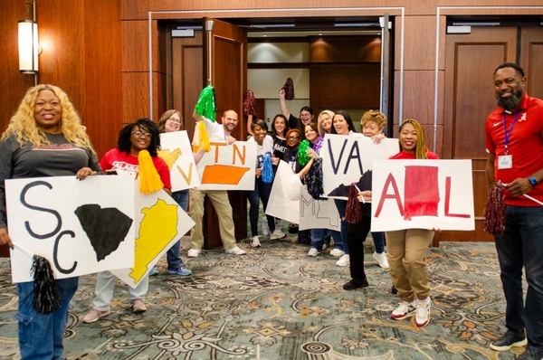 Everyone smiling big while holding various signs for states.