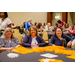 Three woman sitting at a table with several gold pom poms sitting on the table.