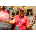 An excited woman laughing and waving around two pom poms.