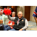 A gentleman in a black vest  holding up a red pom pom.