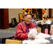 A man in a red jacket sitting at a table full of white pom poms.