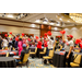 A room full of individuals standing around tables while waving pom poms high in the air.