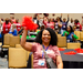 A woman sitting while excitedly waving a red pom pom.