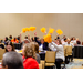 A table full of women sitting in the middle of a room waving around gold pom poms.