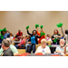 A close up of a woman on the other side of the room dancing and waving green pom poms.