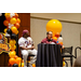 Two individuals sitting at a small round table on stage. One of them is speaking into a microphone.