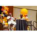 Two men sitting on stage at one of the round tables to address the crowd.