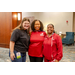 Two women wearing red shirts standing with a woman wearing a black shirt.