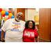 Two individuals wearing glasses with a balloon arch in the background.