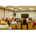 A room full of individuals listening to a speaker standing off to the side.