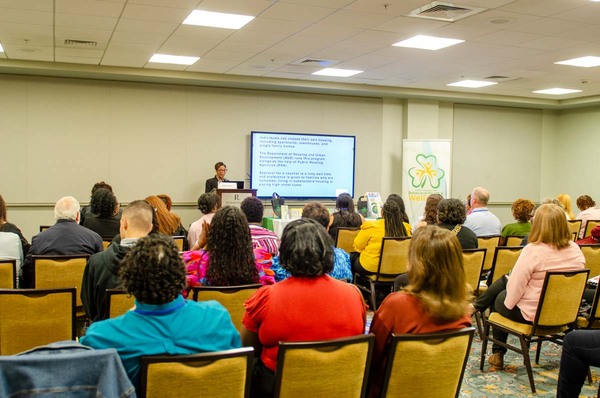 A woman with red glasses standing behind a podium giving a presentation.