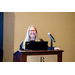 A smiling woman standing behind a podium with a laptop.