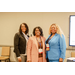 Three women in bright blazers smiling for a group photo.