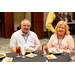 A man and a woman sitting at a dining table eating salads.