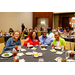 Four individuals leaning in to take a group photo while sitting at a dining table.