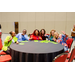 A group of individuals sitting around a table holding up Bingo cards and peace signs.