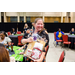 A woman in a black floral shirt holding up a gift card and gift bag.