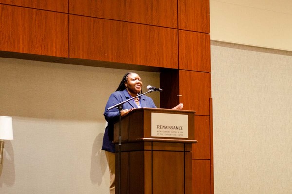 A woman in a blue blazer speaking at a podium that says Renaissance Hotel and Spa at the Convention Center.