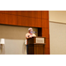 A gentleman in an orange polo speaking at a podium.