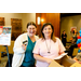 Two women smiling for the camera while one of them holds an Amazon gift card.