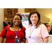 A woman in a red shirt smiling with a woman in a pink shirt.