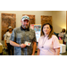 A gentleman in a hat holding up a Chilis gift card while standing next to a woman in a pink shirt.