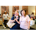 A woman in a blue shirt posing with a woman in a pink shirt while holding a Visa gift card.