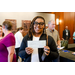 A woman with black glasses holding a check in front of her chest.