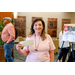 A woman in a pink shirt holding up a check with one hand.